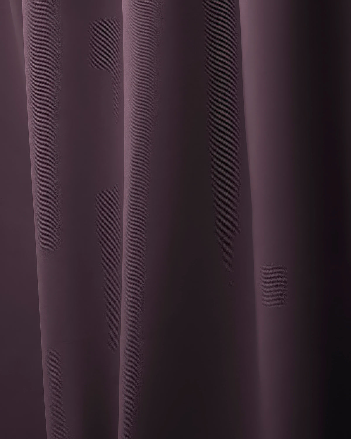 Close-up of dark plum custom curtain fabric with elegant folds, showcasing rich color and luxurious texture for sophisticated window treatments.