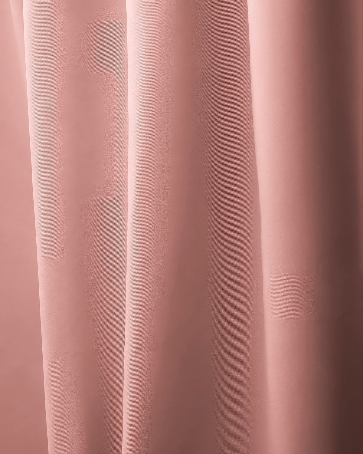 Close-up of rich rose pink custom curtain fabric, showing soft texture and elegant vertical drapery folds for sophisticated window treatments.