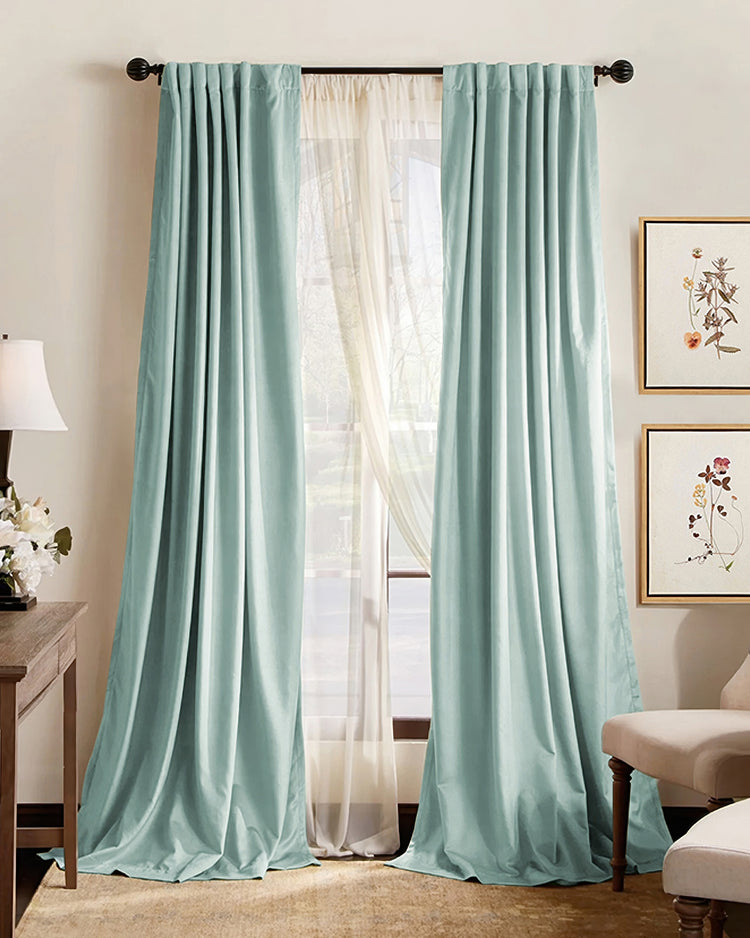 Elegant mint green custom thermal blackout curtains with pinch pleat heading, layered over sheer drapery, complementing home decor.