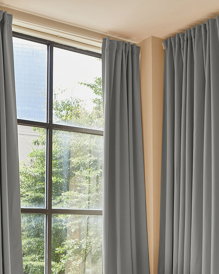Hussein premium custom grey blackout drapery panels with a pleated header, offering thermal & soundproof privacy at a large window.