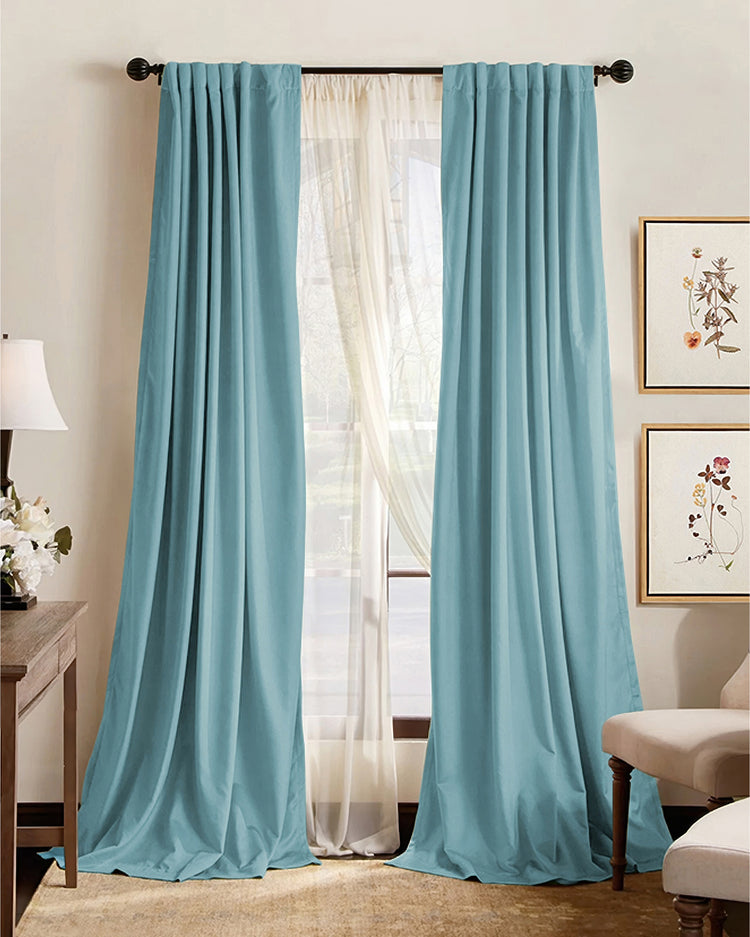 Two teal custom blackout curtains hang over sheer drapery. Premium 4-layer soundproof thermal window treatment for light & privacy control.