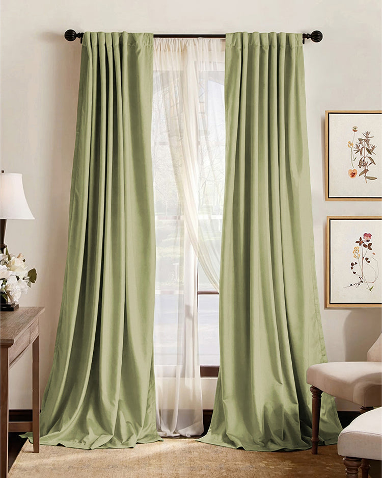 Elegant pale green custom blackout curtains with pleated headers, layered over sheers, providing privacy & light control in a stylish room.