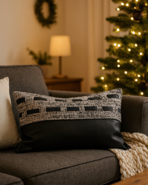 Juliette lumbar pillowcase on a sofa, showcasing textured gray fabric with faux leather accents & a solid black faux leather base.