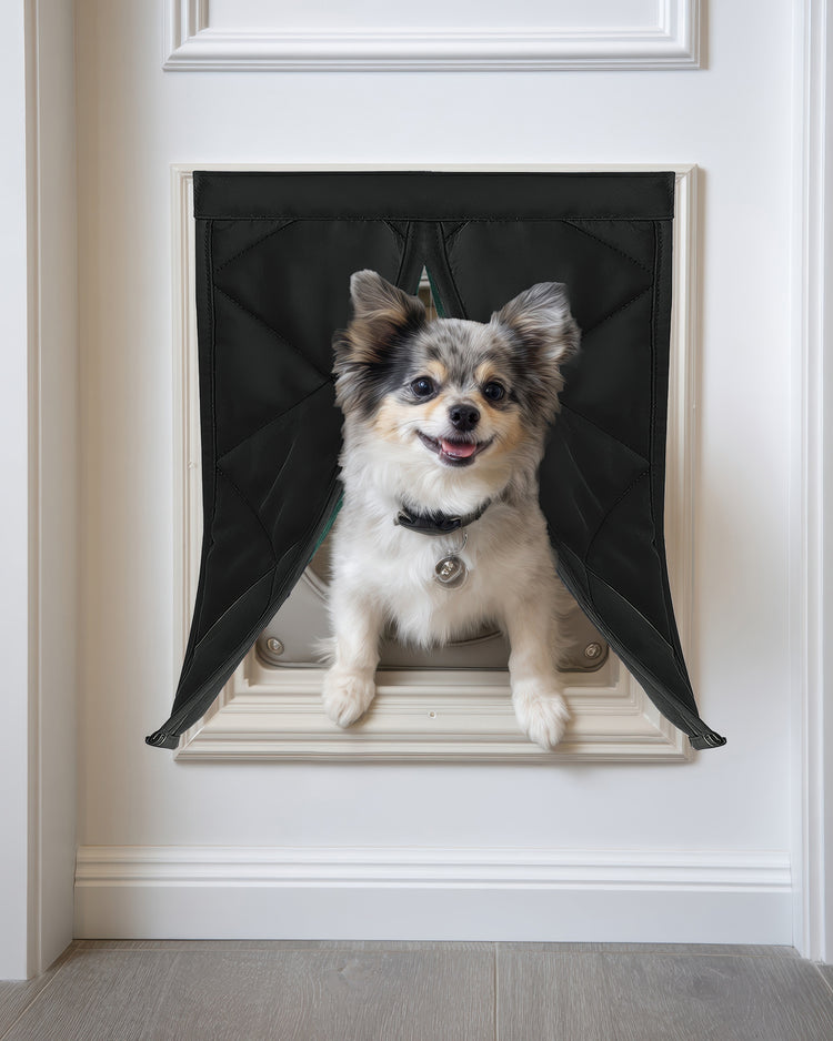 Happy fluffy merle dog peeking through black Oxford thermal custom pet door cover installed in a white door.