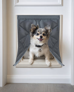 Happy dog exits through a gray quilted Oxford thermal custom pet door cover, ensuring cozy warmth & easy access for pets.