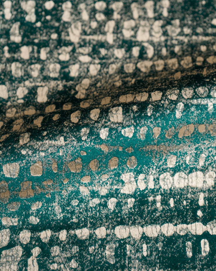 Close-up of teal velvet fabric featuring a metallic pebbles foil print for elegant custom window treatments.