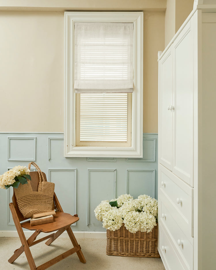 Custom Thistle sheer Roman shade with a sleek flat fold, offering light filtering in a classic room with blue wainscoting and decor.