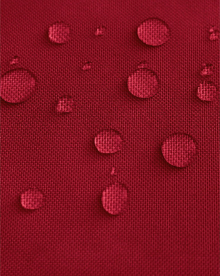 Close-up of red UVShield™ outdoor fabric swatch with visible water repellency, perfect for durable outdoor drapery.