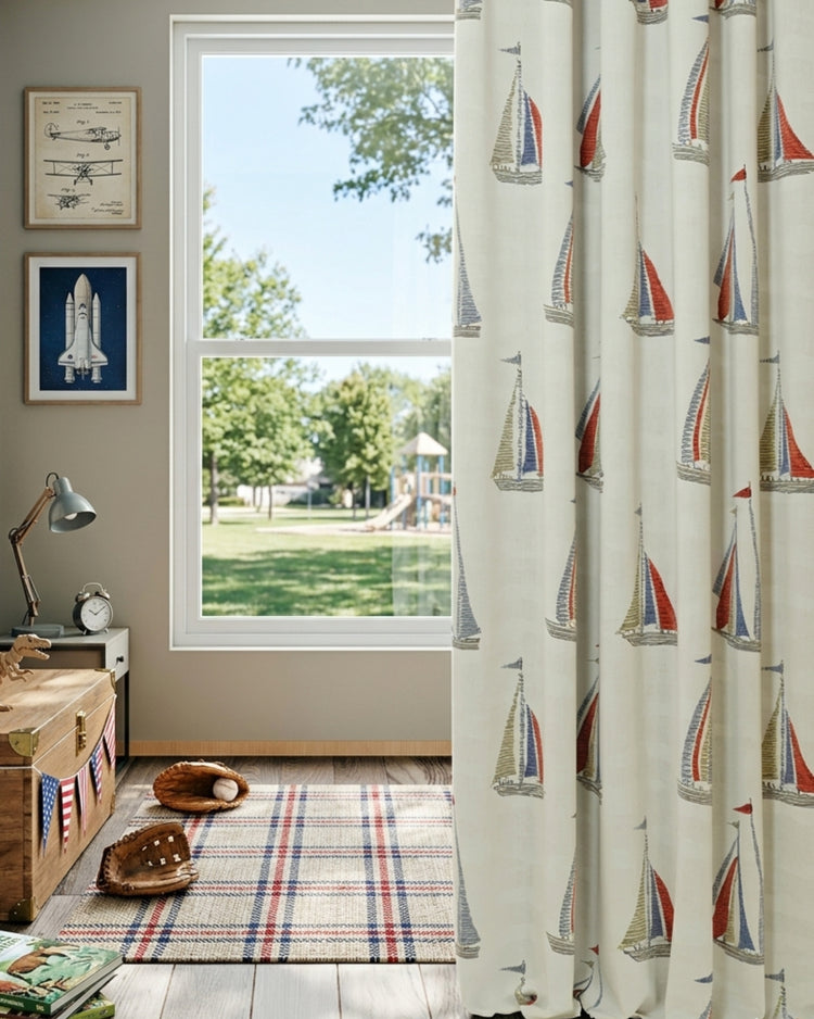 Voyage Patterned Kid's Custom Curtain with vibrant red & blue sailboats, providing playful light control for a nursery window overlooking the sea.