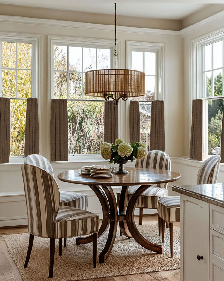 Brown Zoe Linen Look Custom Cafe Curtains on multiple windows in a bright dining nook with a wooden table and striped chairs.