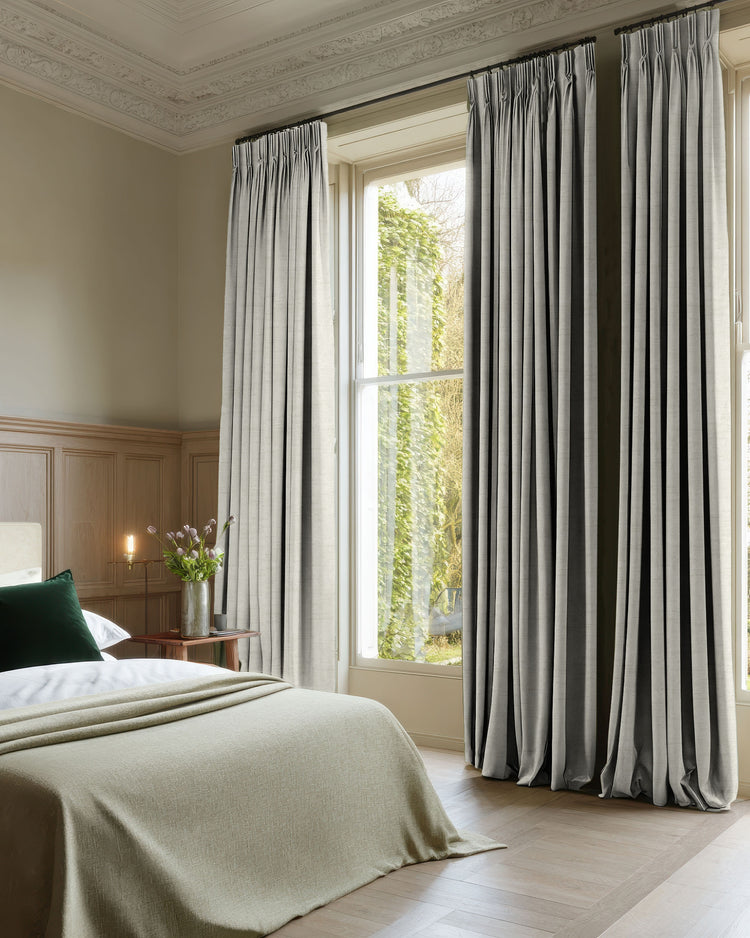 Luxurious light grey jacquard blackout custom curtains with elegant pleats, perfectly dressing a bedroom window for tailored light control.