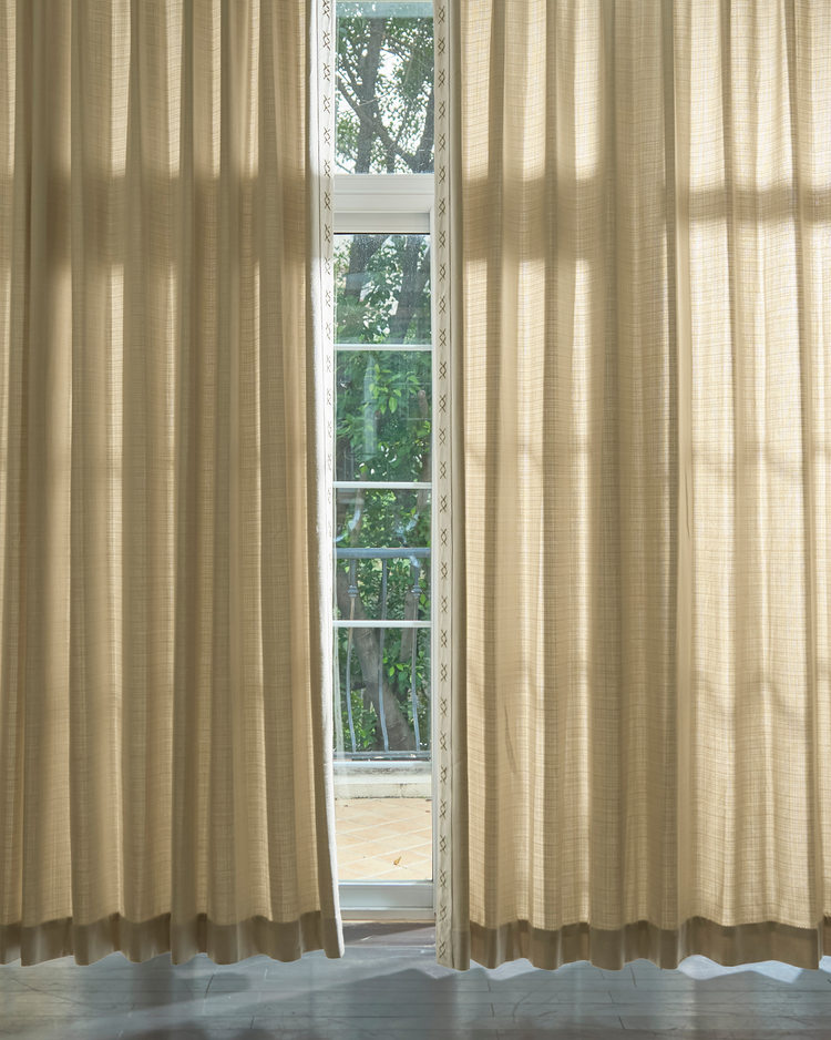 Arden textured custom drapery in natural beige with decorative X-pattern trim, offering light-filtering over a window.