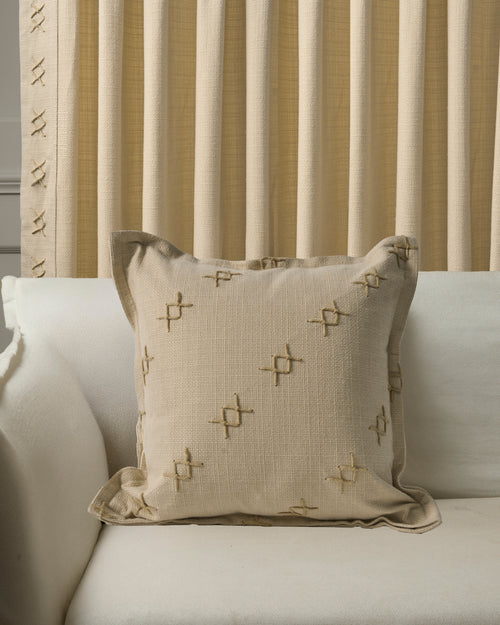 Arden textured yarn stitched throw pillowcase with 'X' embroidery on a sofa, complementing custom pleated natural linen drapery.