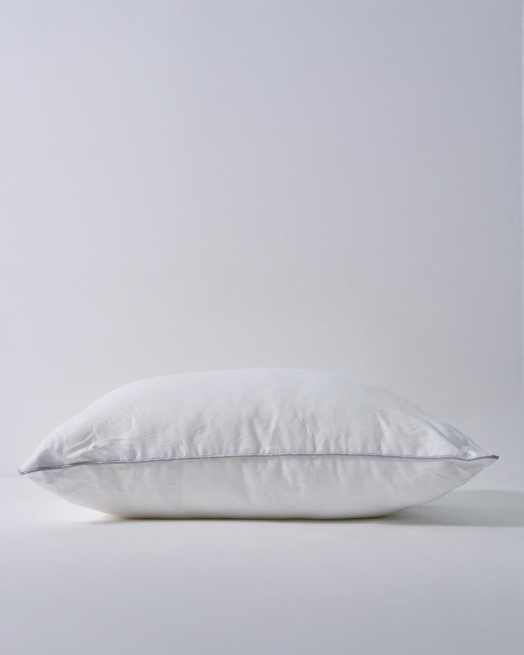 Plump white feather lumbar pillow insert with subtle grey piping, providing soft support for custom home decor.