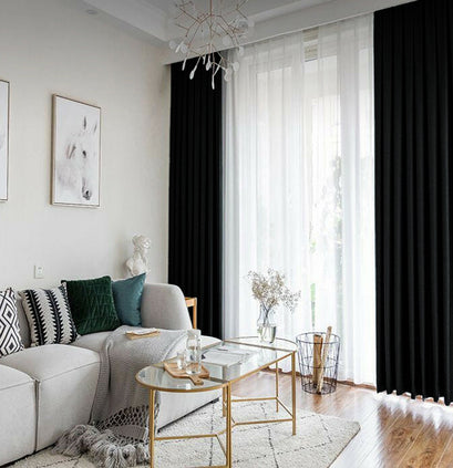 Floor-length black velvet custom curtains flanking white sheers in a stylish living room, providing tailored light control.