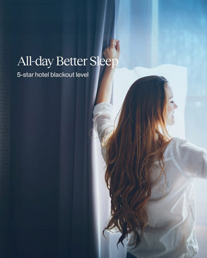 Woman opening a dark grey custom blackout curtain, allowing natural light in, showcasing precise light control and privacy.