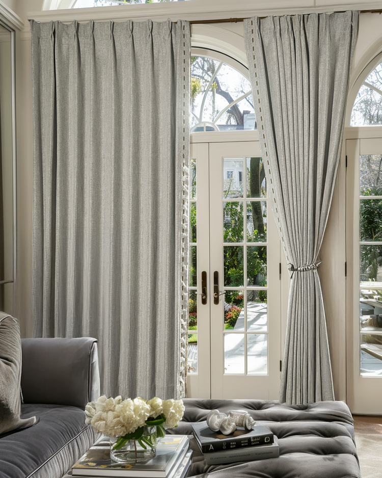 Custom Cleo textured linen blend drapery with elegant faux leather trim, adorning arched French doors in a refined living space.