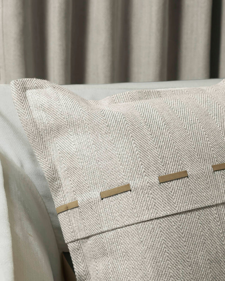 Beige Cleo textured throw pillowcase with herringbone weave and faux leather accents, styled with elegant custom drapes.