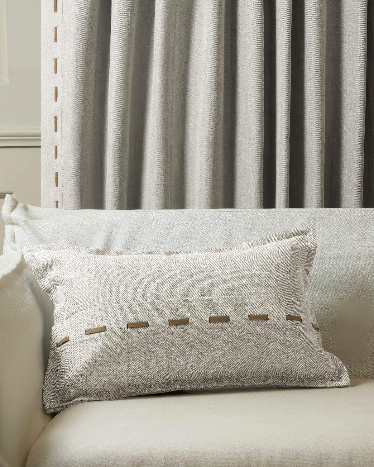 Cleo textured micro-herringbone lumbar pillowcase with faux leather lacing on sofa, coordinating custom drapery.