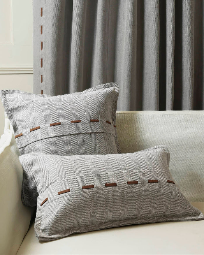 Cleo textured gray herringbone faux leather laced throw pillowcases on a light sofa, complementing custom window drapery.