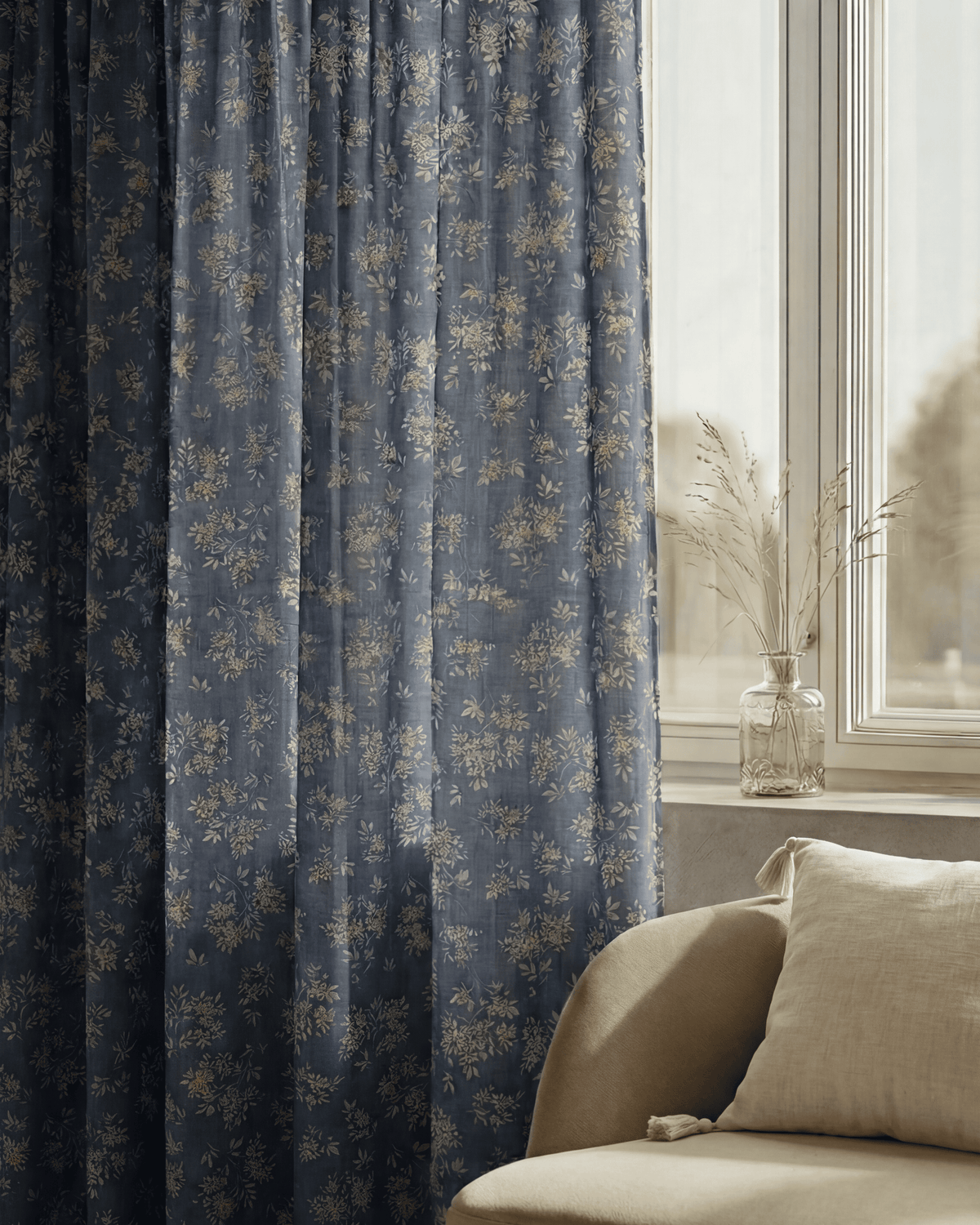 Haven blue linen blend floral patterned custom curtains beside a window with a glass vase and cream sofa.