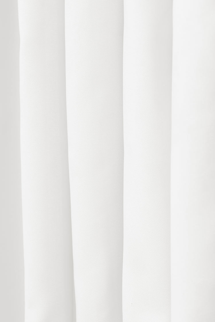 Close-up of white canvas waterproof outdoor curtain fabric, showcasing its subtle weave and elegant vertical folds.