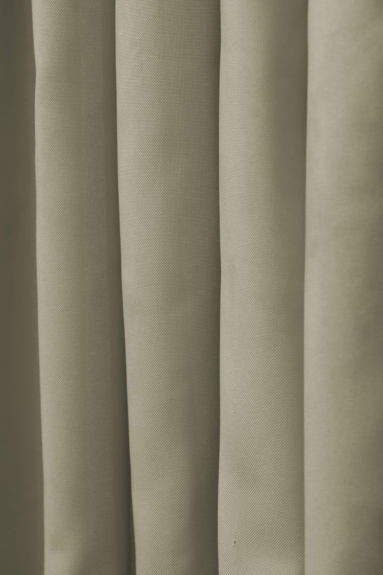 Light olive FadeShield™ canvas waterproof custom outdoor curtain fabric with visible weave and soft drapes for window treatments.