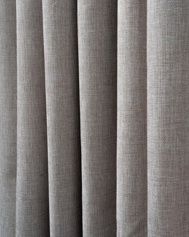 Detailed texture of a heavyweight, 100% blackout custom curtain fabric, showing its tight woven pattern in a neutral taupe.
