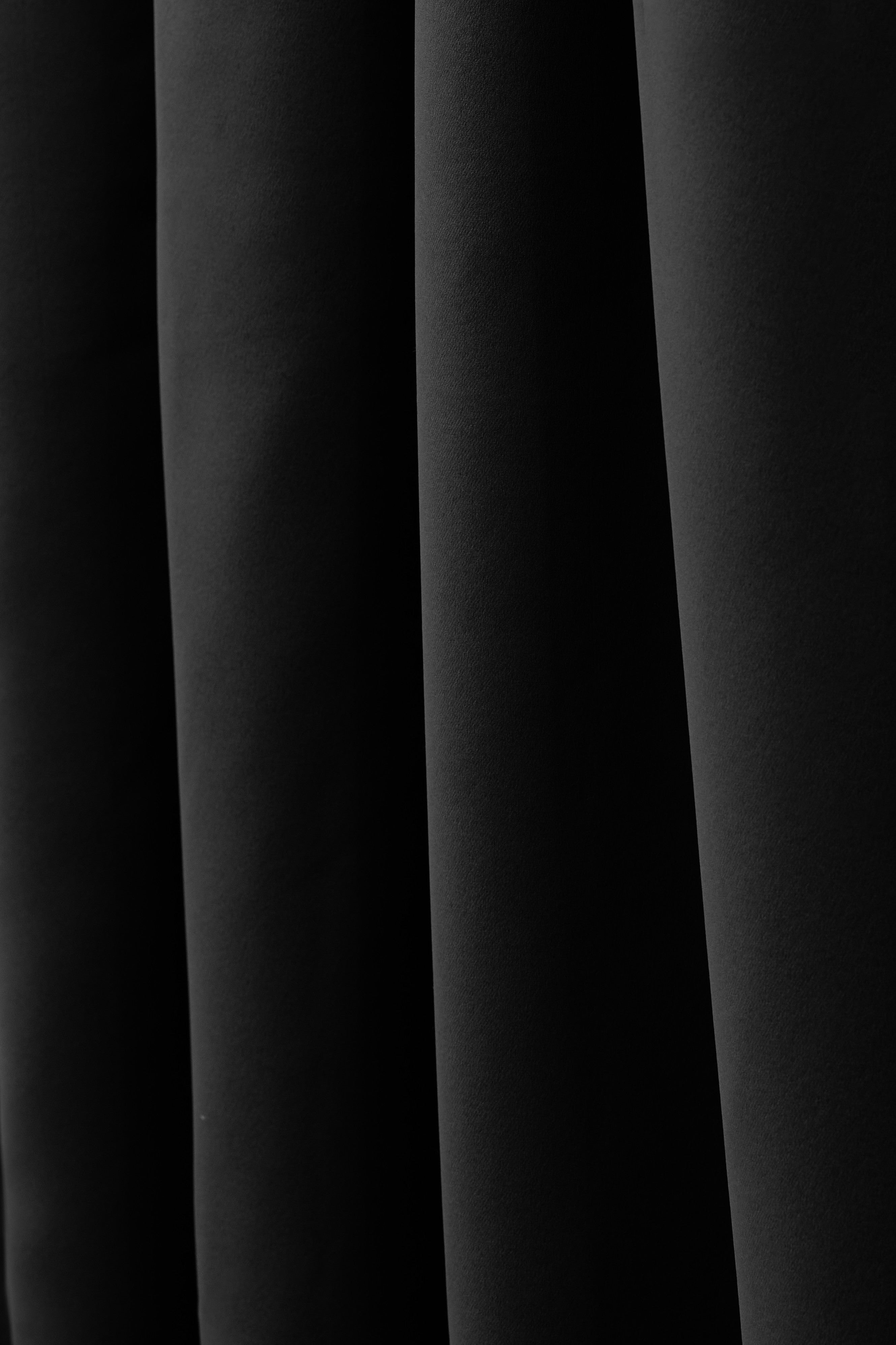 Custom Frisian flame retardant curtain fabric in deep black, showcasing rich texture and elegant folds for superior light control & privacy.
