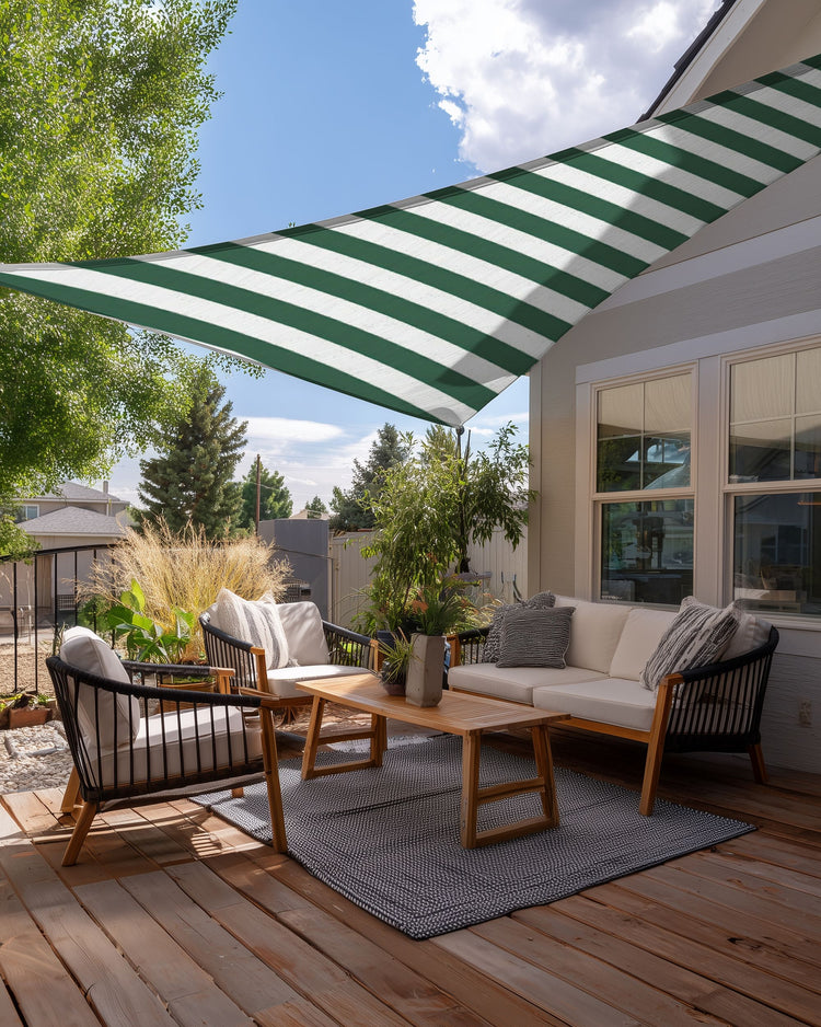 UVShield green and white striped waterproof triangle sun shade sail covering a stylish outdoor patio deck with lounge furniture.