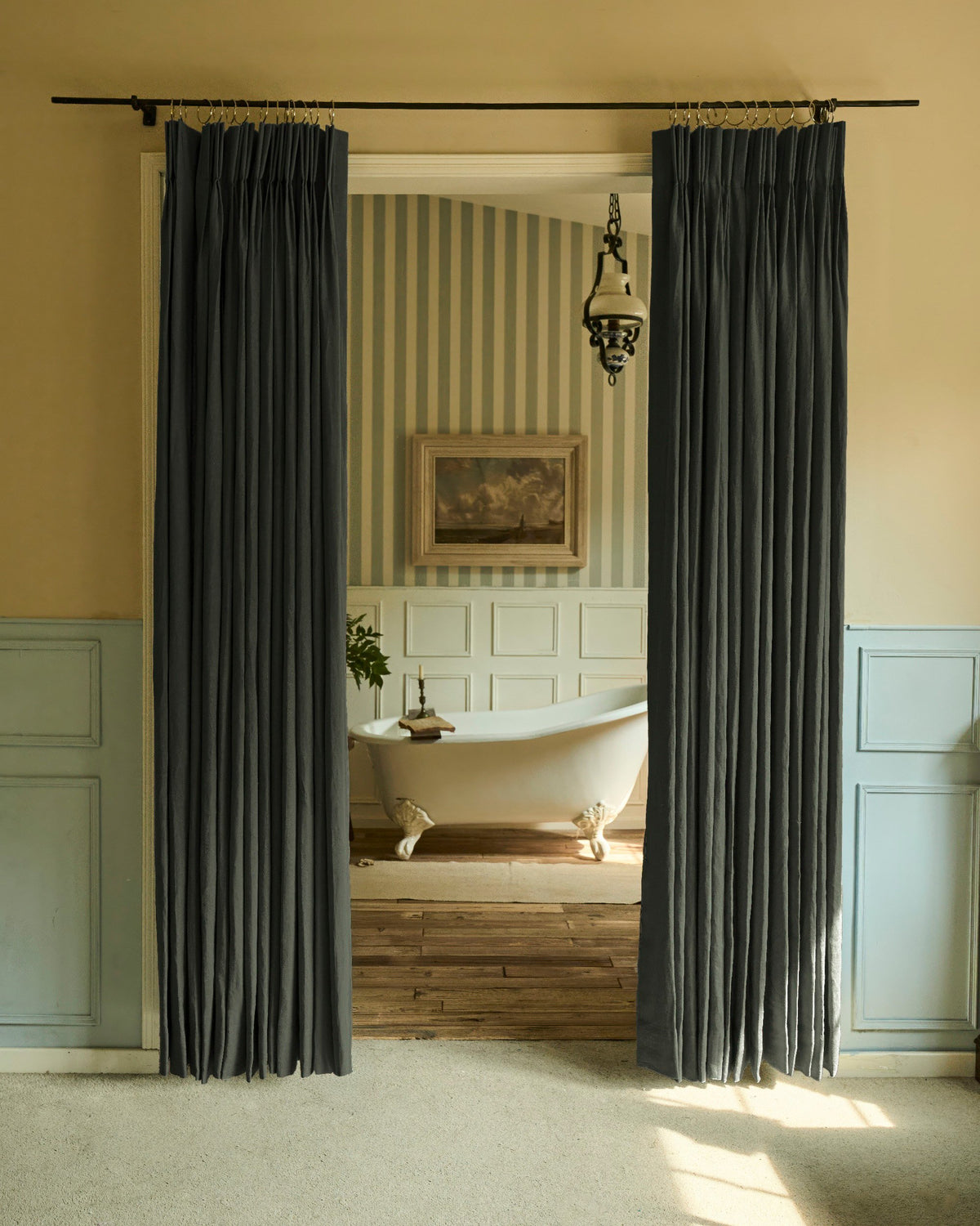 Charcoal grey Helena 100% Linen custom curtains with elegant pleats, hanging as doorway drapery, revealing a luxurious clawfoot tub bathroom.