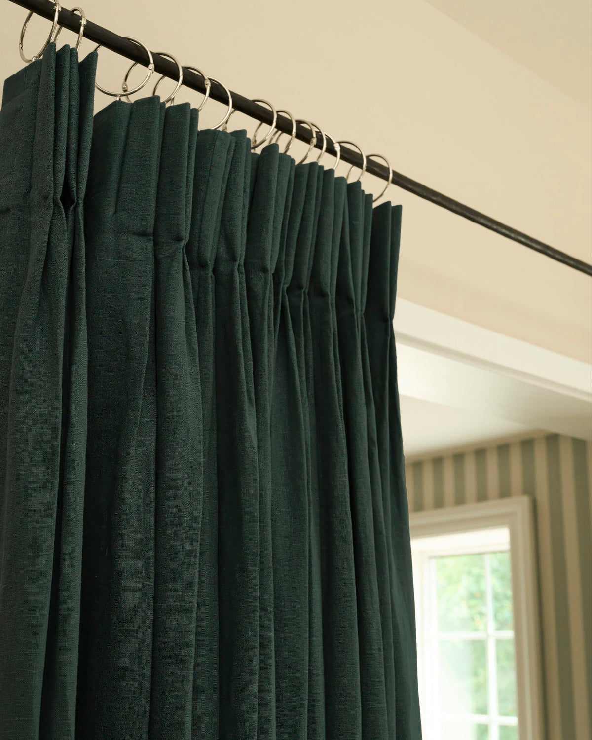 Helena dark green pure linen custom drapery, featuring a tailored pleated header with metal rings on a rod.