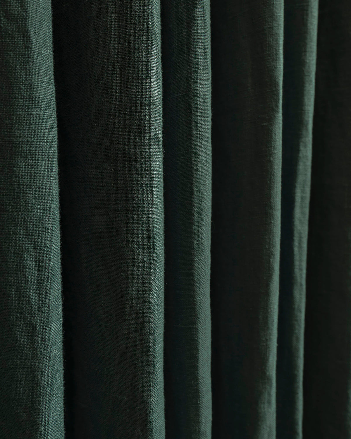 Deep green 100% linen custom drapery fabric, highlighting its natural weave and elegant folds.