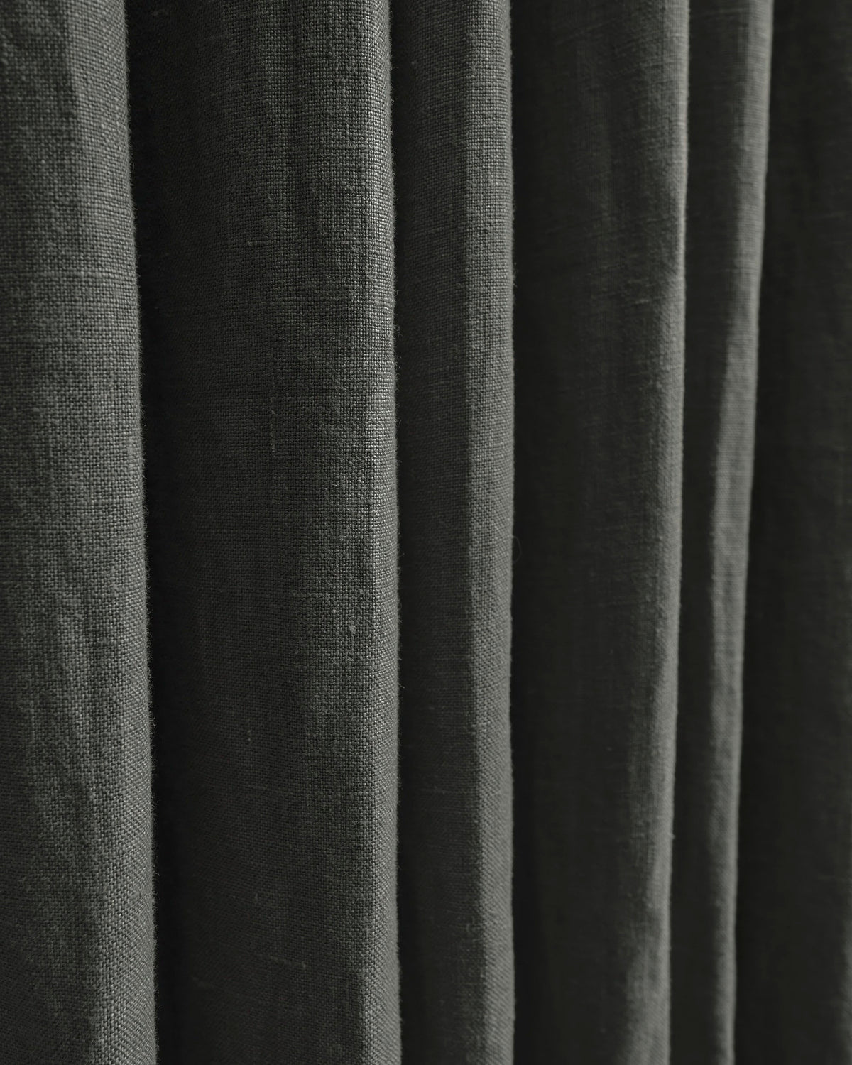 Close-up of dark grey 100% linen custom curtains showing natural fabric texture and elegant vertical folds.