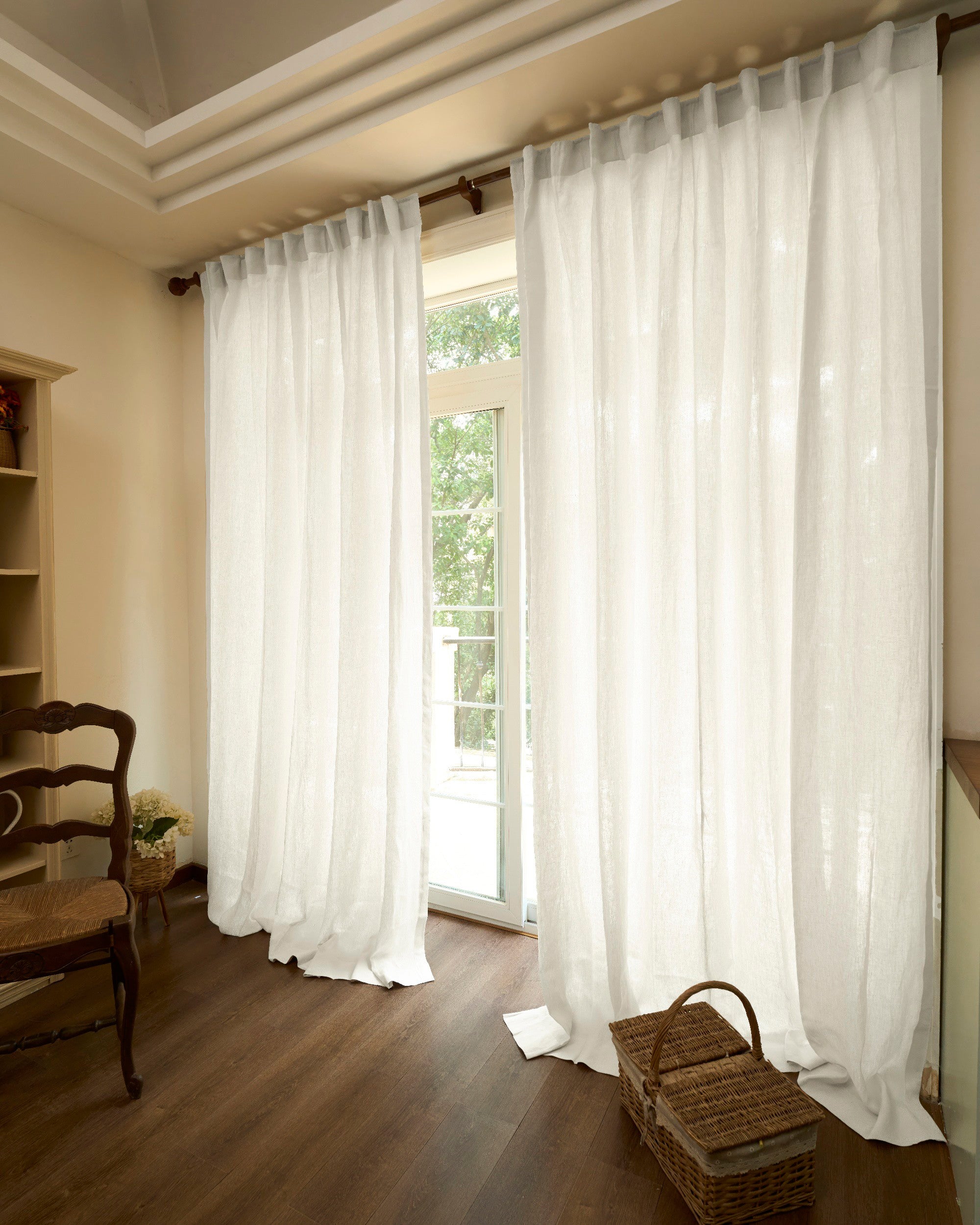Helena pure white 100% linen custom curtains hanging gracefully on a wooden rod, softly puddling on dark wood floors.