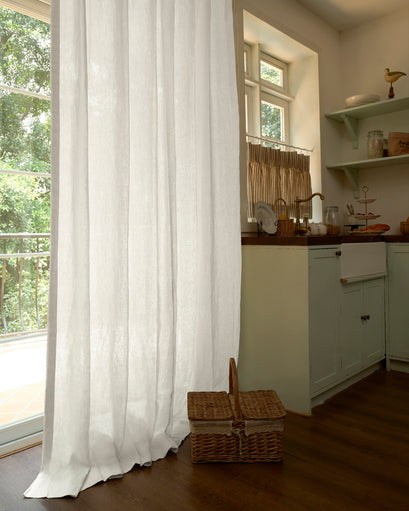 White Helena 100% linen custom sheer curtains elegantly draped by a window overlooking greenery, blending privacy & natural light.
