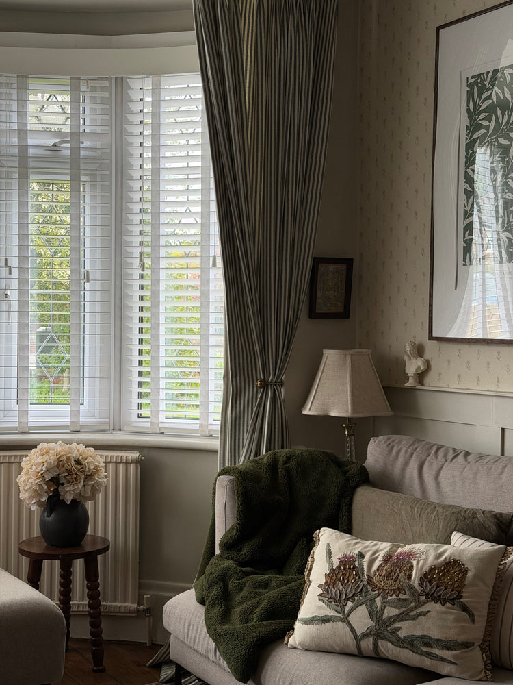 Living room with a couch, decorative pillows, and a window with blinds.