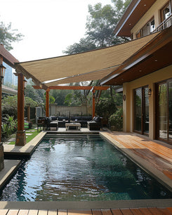 Waterproof UVShield™ custom rectangle sun shade sail provides stylish shade over a luxury outdoor patio with a pool & lounge.