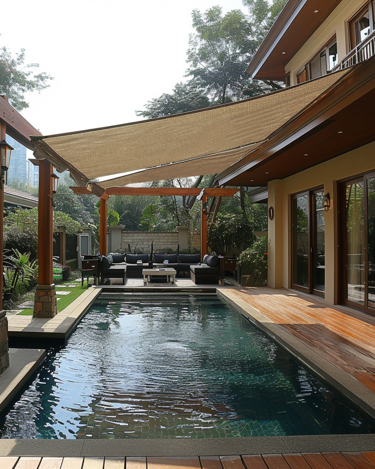 Waterproof UVShield™ custom rectangle sun shade sail provides stylish shade over a luxury outdoor patio with a pool & lounge.
