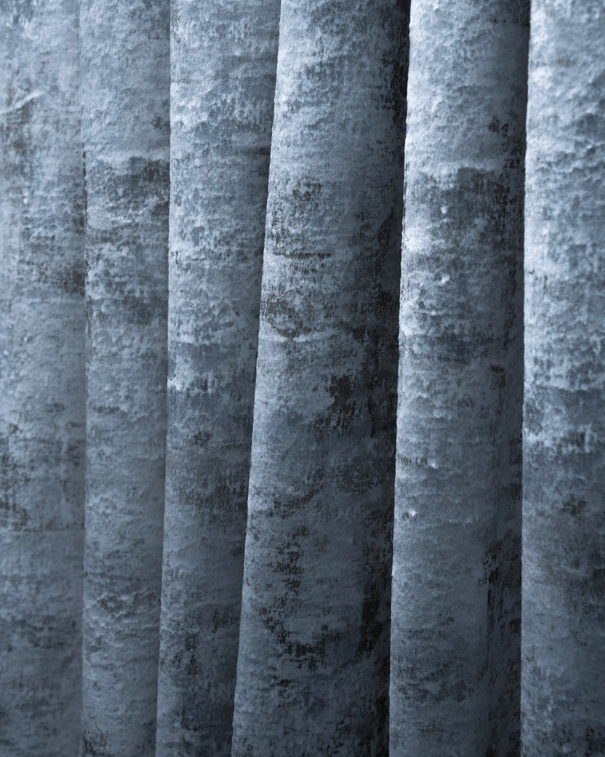 Close-up of luxury blue-grey velvet custom curtain with distressed Impression foil printed pattern, showcasing elegant folds & texture.