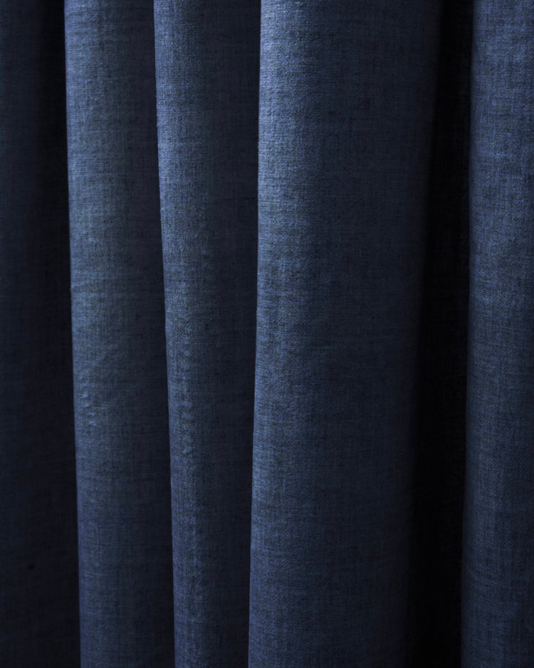 Close-up of deep navy velvet custom curtain fabric with visible linen-like texture and elegant folds, showing its heavyweight drape.