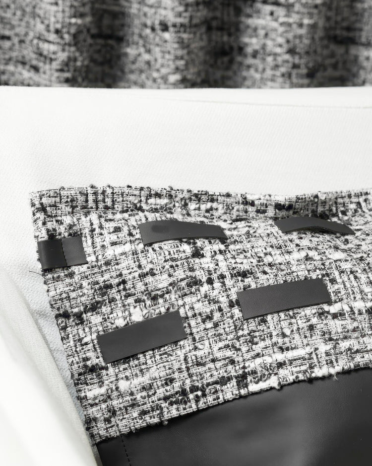 Close-up of Juliette textured throw pillowcase in black and white tweed with faux leather straps and a solid black bottom panel.