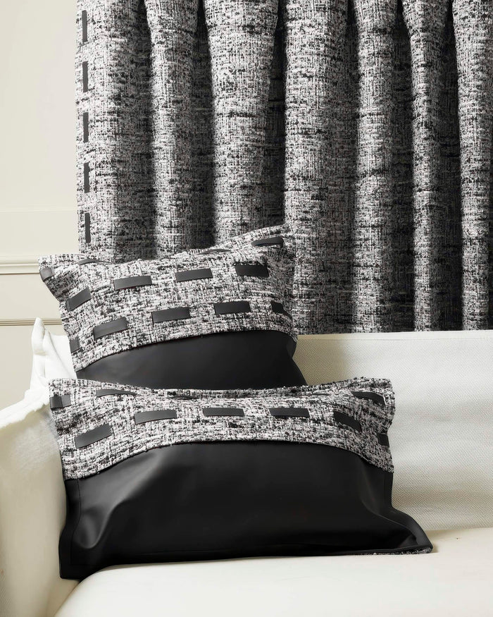 Juliette textured faux leather throw pillowcases in black and white tweed, with black leather trim, styled on a sofa with matching custom drapes.