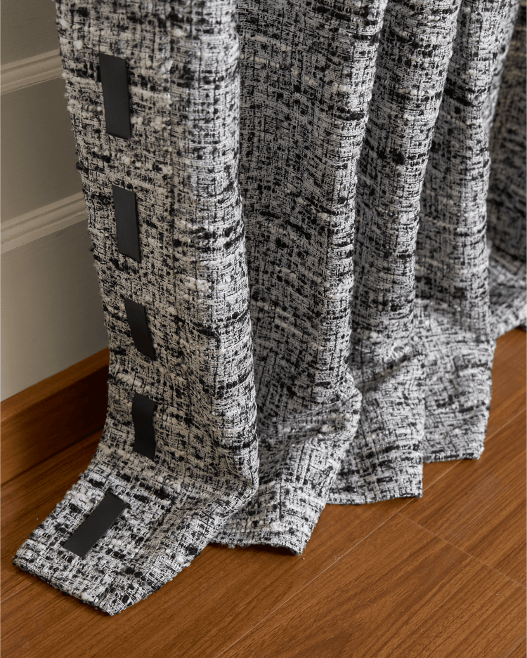 Close-up of Juliette wool blend custom curtain fabric with black & white texture, adorned with dark rectangular trims.
