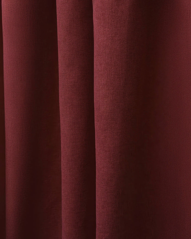 Close-up of Laborien linen look textured custom curtain fabric in deep burgundy, showing rich folds and woven texture.