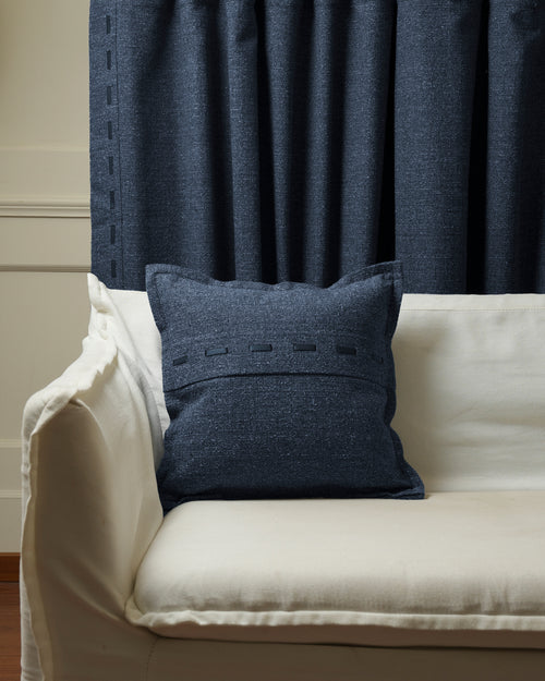 Luna dark blue linen blend throw pillowcase, featuring faux leather lacing, on a white sofa with coordinating custom drapery.