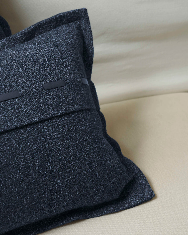 Close-up of Luna linen blend throw pillowcase, textured navy fabric with black faux leather lacing detail on cream sofa.