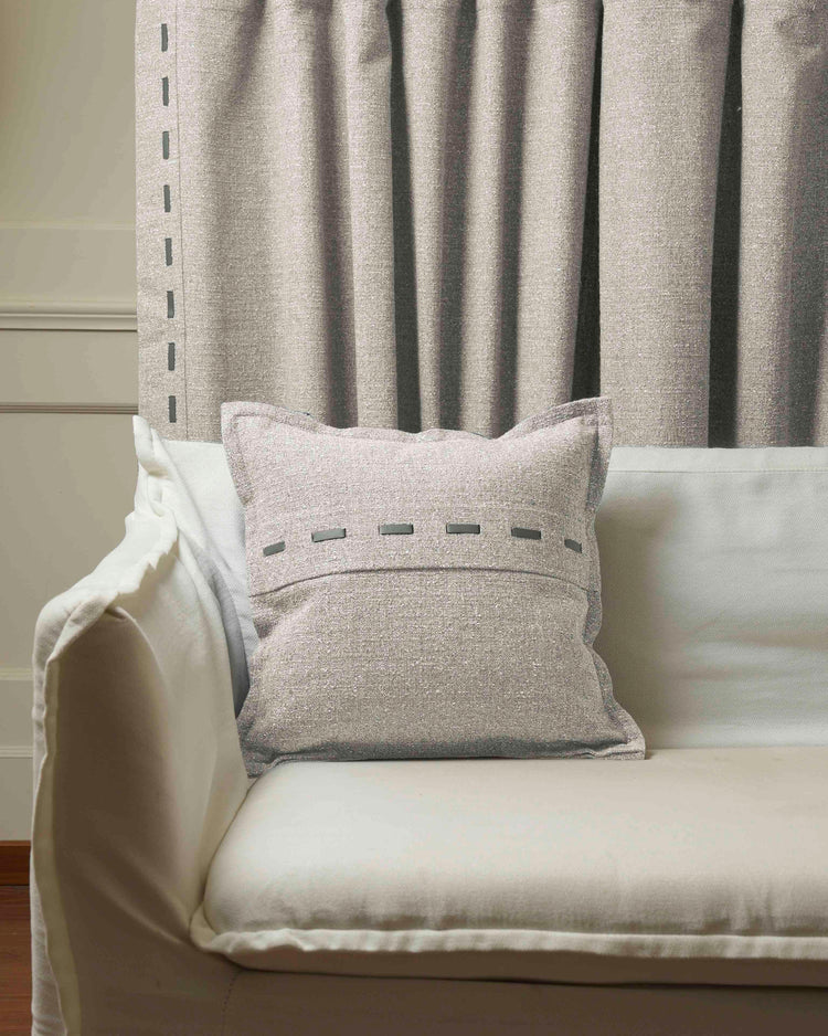 Light gray Luna Linen Blend faux leather laced throw pillowcase on a white sofa, with matching custom linen drapery.