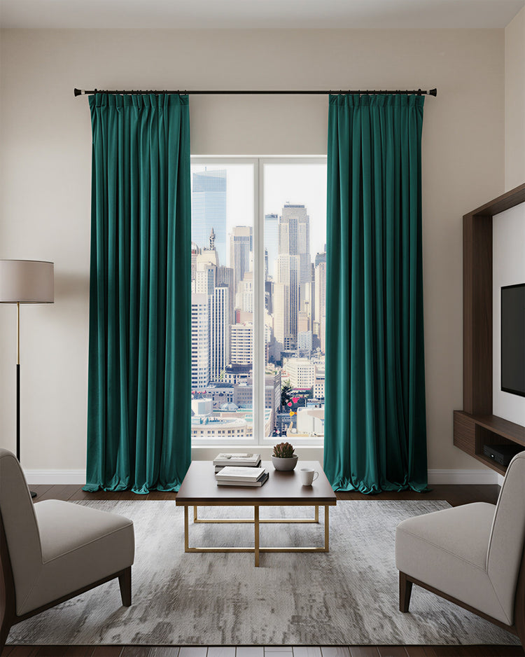 Heavyweight teal velvet blackout custom curtains in a modern living room, offering thermal & soundproof benefits, overlooking a cityscape.
