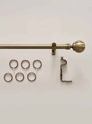 Brass curtain rod with hardware on a light beige background